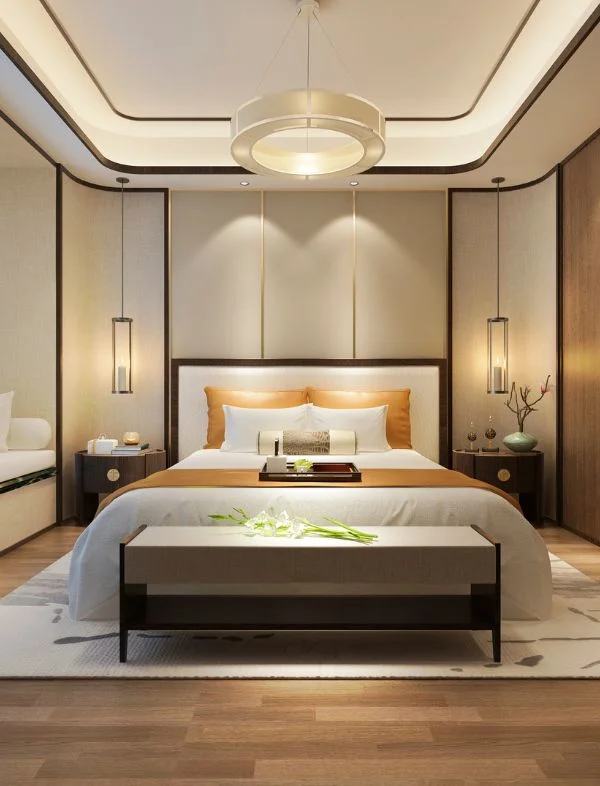 Luxury bedroom interior with a modern tray false ceiling, halo ring chandelier, and symmetrical pendant lights beside a cream upholstered headboard.