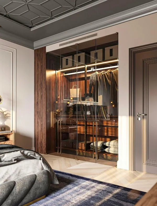 Modern luxury bedroom featuring a built-in glass door wardrobe with integrated LED shelving, a decorative crown-molded ceiling, and a blue textured area rug.