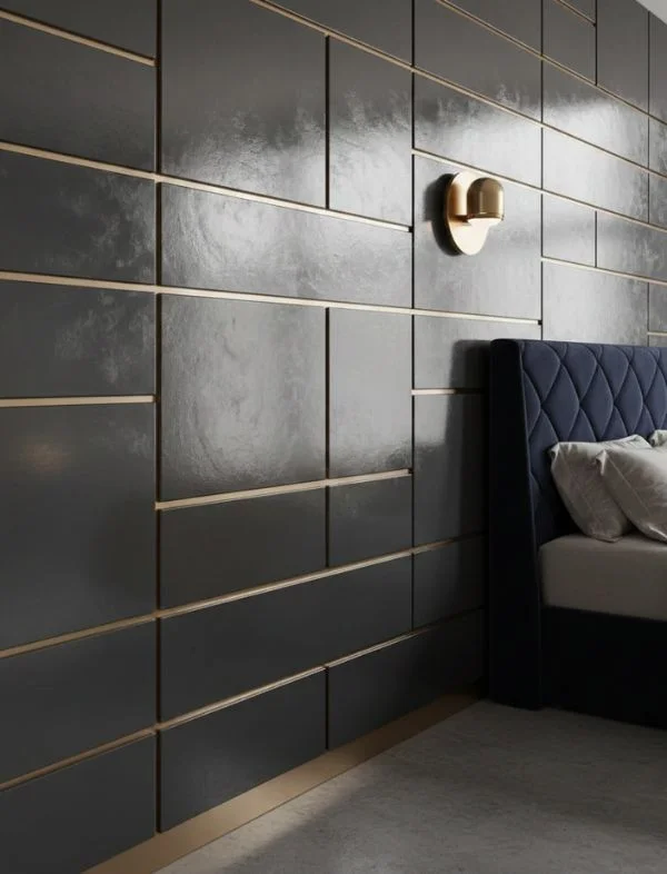 Luxury bedroom featuring a bespoke charcoal grey textured wall panel system with horizontal and vertical gold metal inlays, a brass globe wall sconce, and a navy blue tufted velvet headboard.